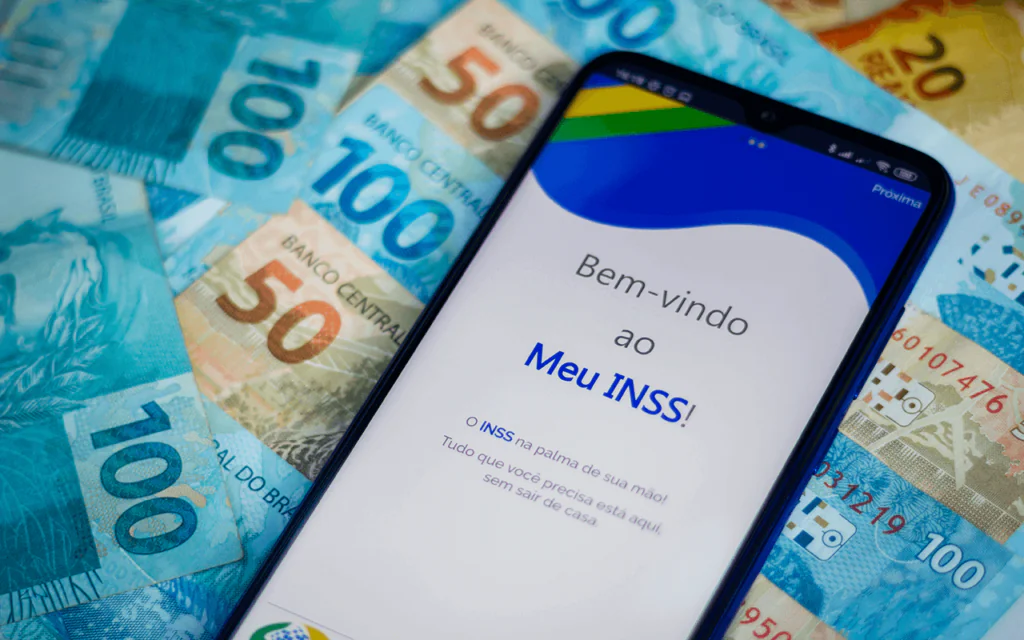 Celular com Meu INSS sobre notas de real